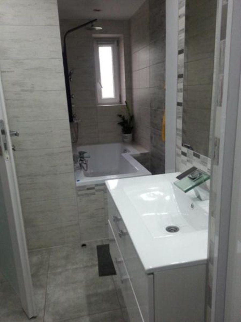 A modern bathroom with a white sink, a bathtub, and a shower area.