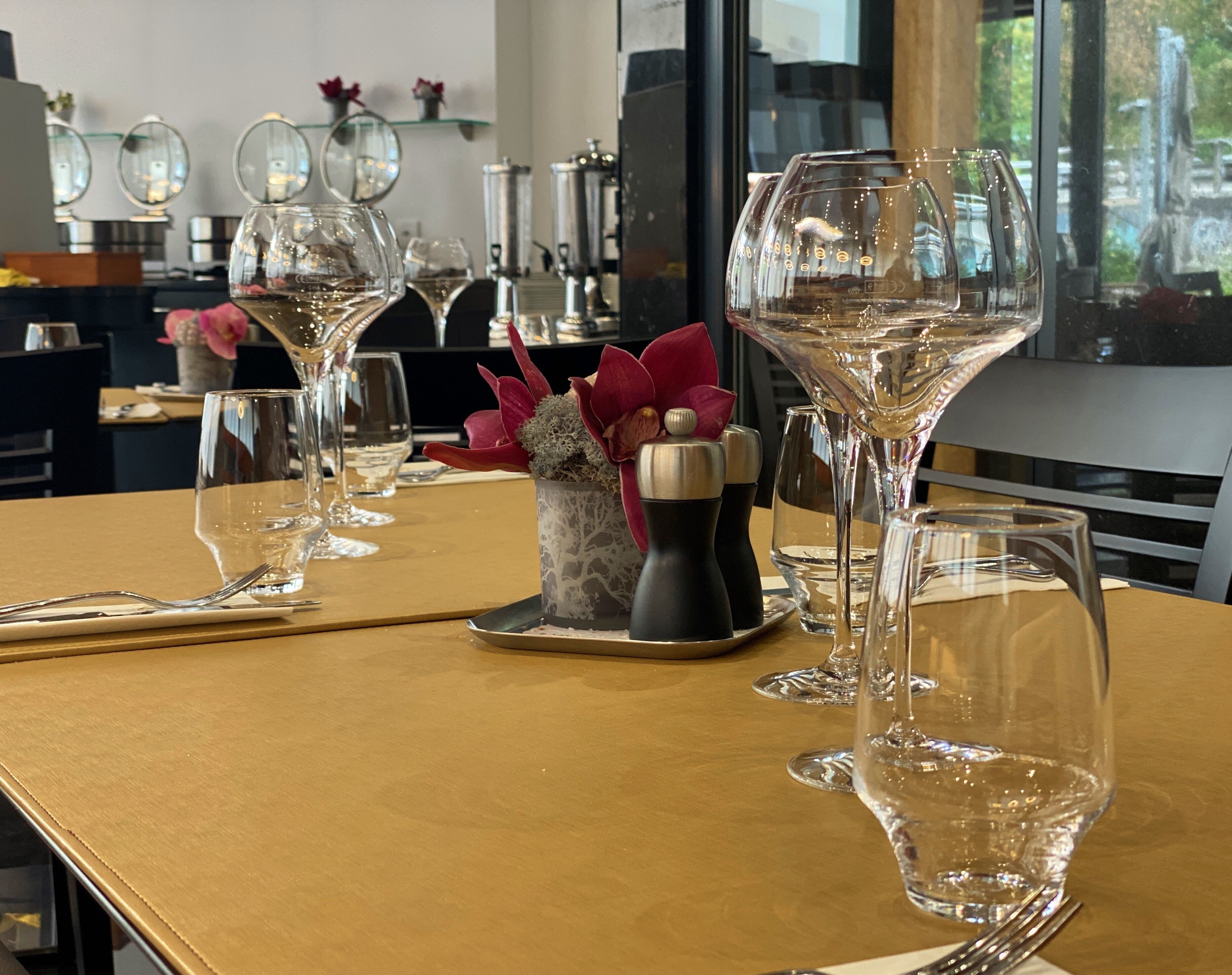 A table set with wine glasses, a salt and pepper set, and a decorative flower arrangement.