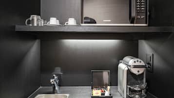 A compact kitchenette with a microwave, coffee machine, and a small drawer with snacks.