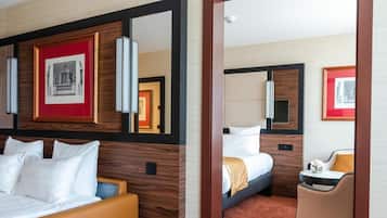 A hotel room with a bed, a seating area with a chair, and a mirror.