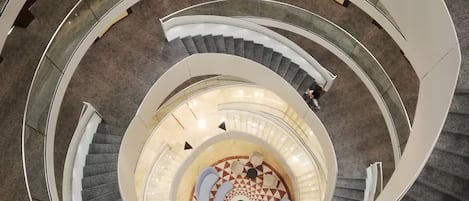 Eine Wendeltreppe mit einer zentralen Sitzgruppe und einem Boden mit geometrischem Muster.