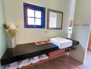 A bathroom with a white sink, a mirror, a window with blue trim, and towels on a shelf. - C'est La Vie (Magong)