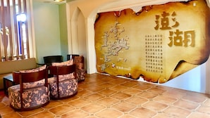 A reception area with a large map on the wall, several cushioned chairs, and a tiled floor. - C'est La Vie (Magong)