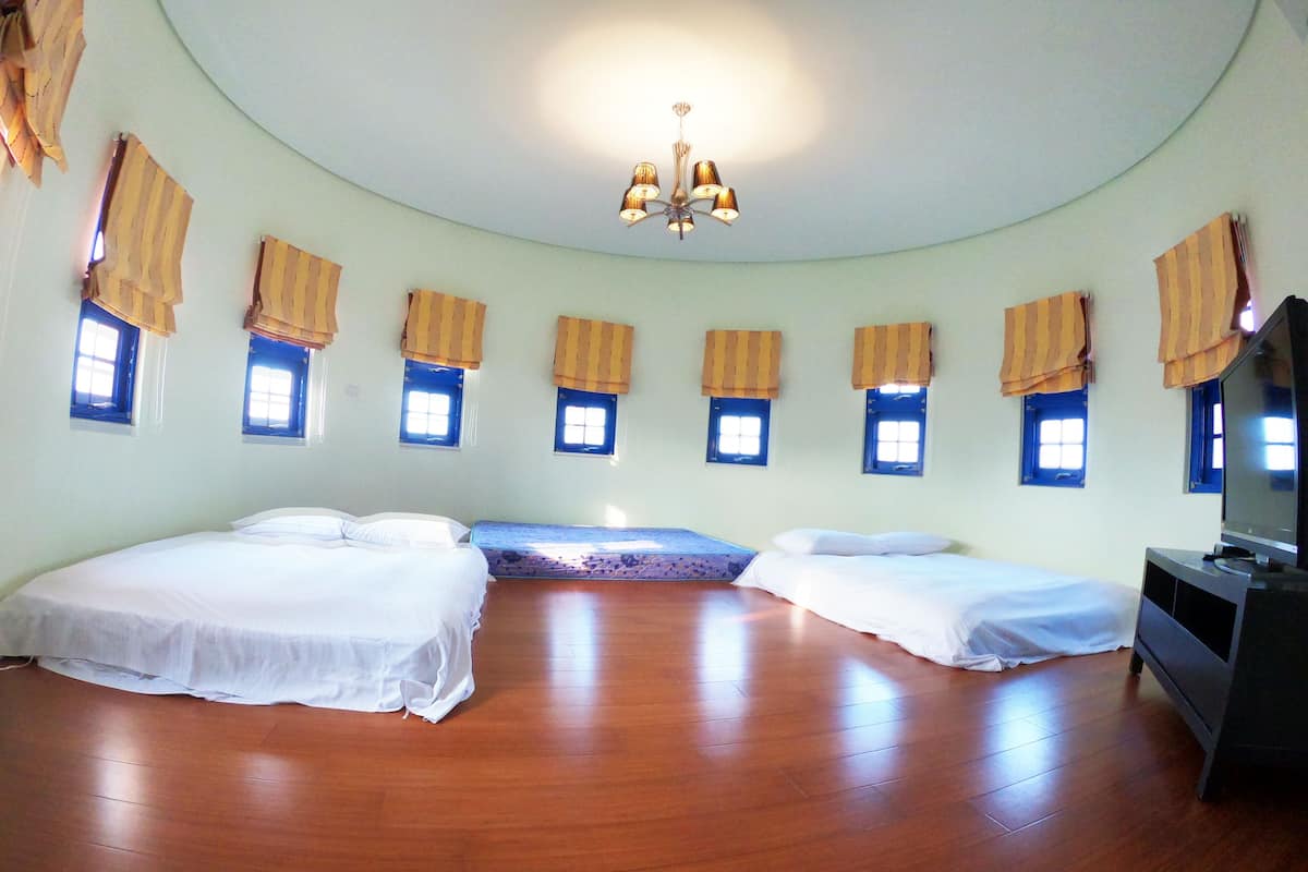 A room with two beds, a television, and a chandelier.