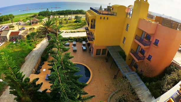 A yellow building with a pool and outdoor seating, overlooking a beach. - C'est La Vie (Magong)