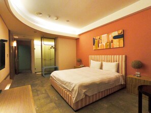 A hotel room with a bed, bedside table, and a small desk. - C'est La Vie (Magong)