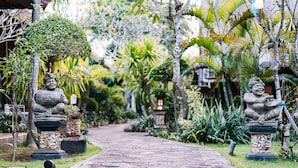 A pathway flanked by stone statues and lush tropical vegetation. - Bunda 7 Bungalow (Lembongan Island)