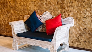 A white upholstered sofa with blue and red cushions against a woven bamboo wall. - Bunda 7 Bungalow (Lembongan Island)