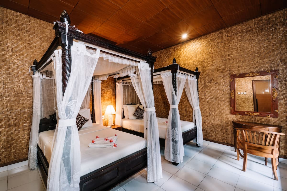Un lit à baldaquin blanc, un bureau en bois et un miroir au mur.