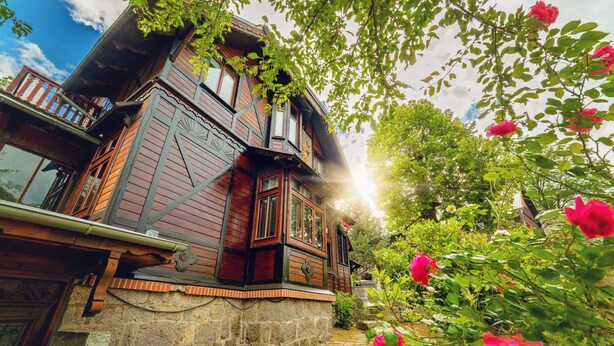 A traditional wooden house with a stone foundation, a balcony with railings, and a garden with blooming flowers. - EverySky Piastowska1 Karpacz (Karpacz)