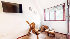 A room with a wooden sculpture, a small table with a kettle, and a window with a view. - EverySky Piastowska1 Karpacz (Karpacz)