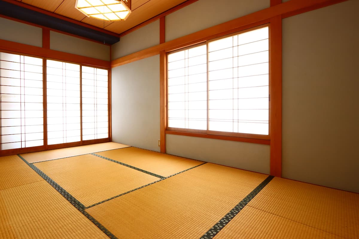 Een traditionele Japanse kamer met tatami vloerbedekking, shoji schermen en een hangende lamp.