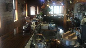 Een keuken met houten wanden, een groot raam en diverse keukenapparaten.