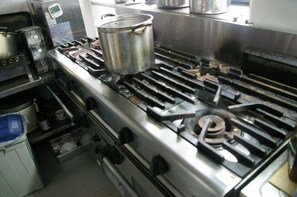 Une cuisine professionnelle équipée d’appareils en acier inoxydable, notamment une grande cuisinière et une casserole posée dessus.