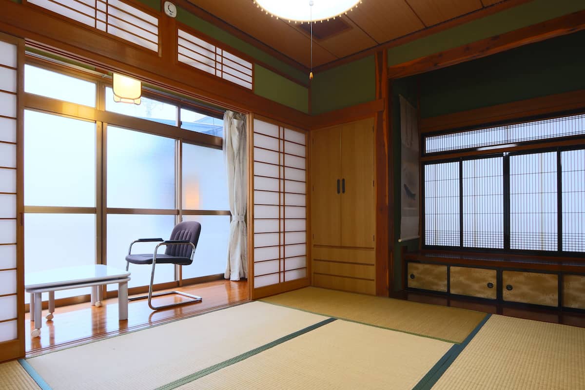 Een traditionele Japanse kamer met tatami vloerbedekking, een lage tafel met een stoel en schuifdeuren.