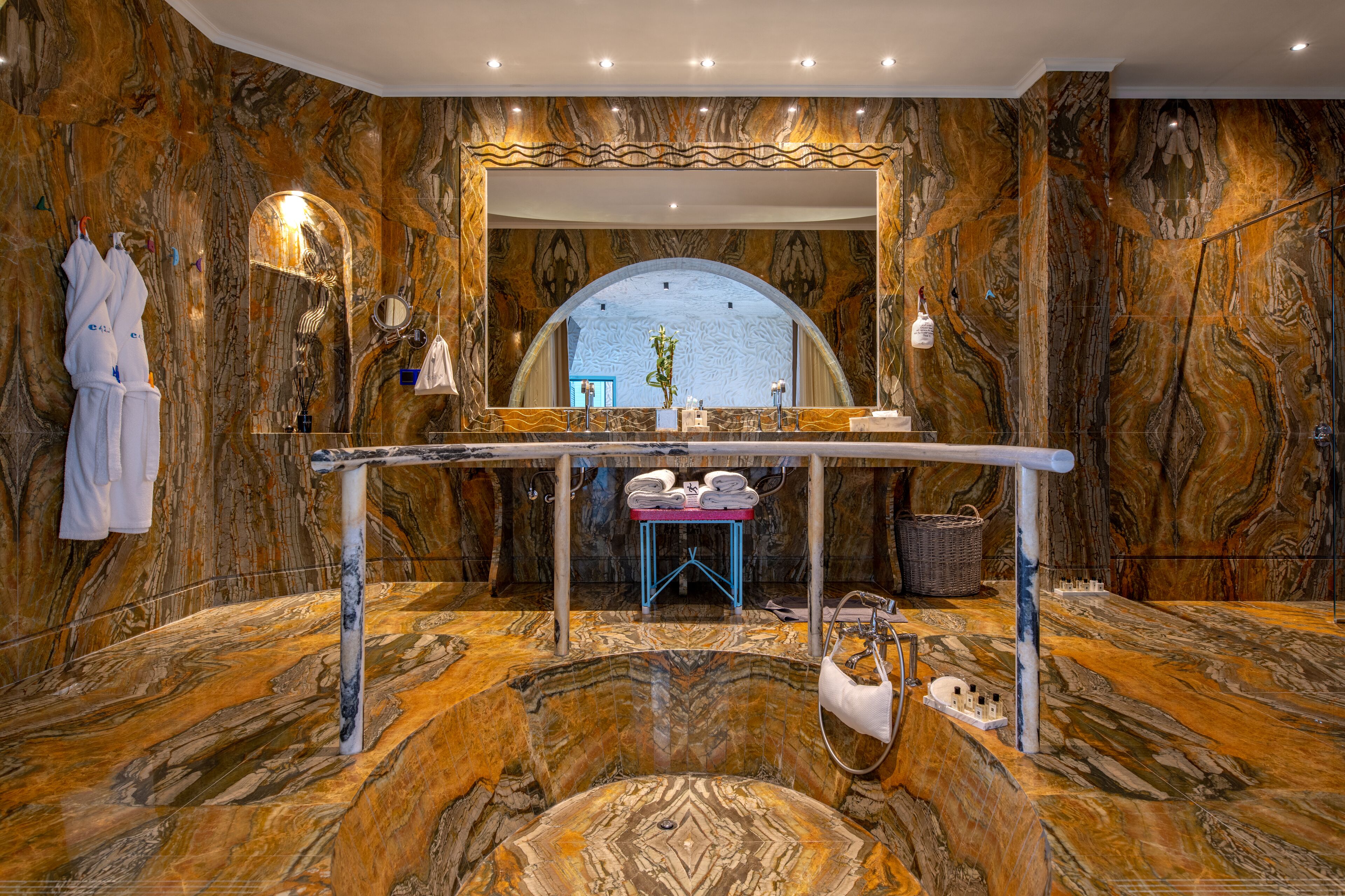 Un baño lujoso con paredes de mármol, un espejo grande y una bañera.