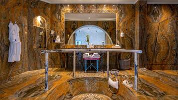 Un baño lujoso con paredes de mármol, un espejo grande y una bañera.