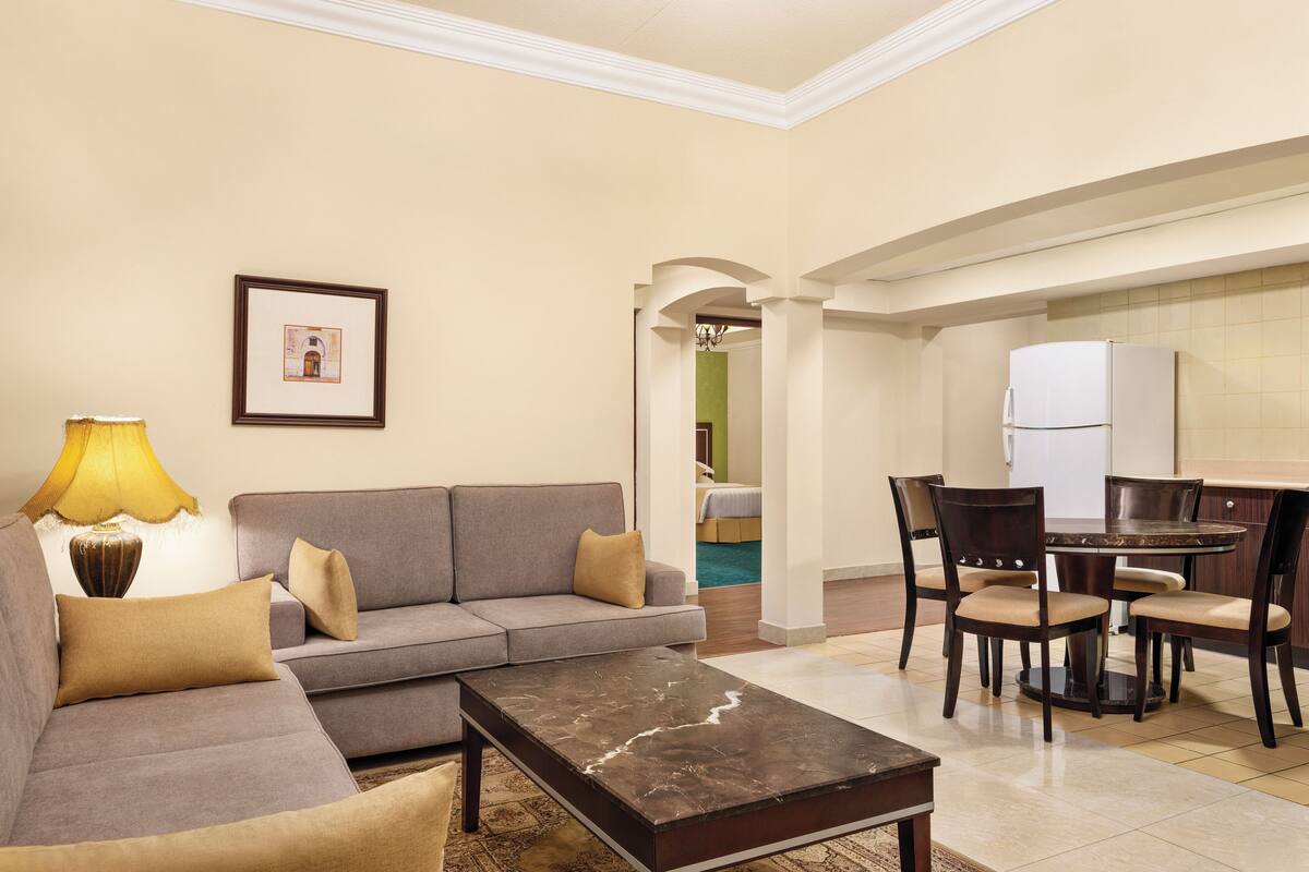 A living room with a sofa, a coffee table, and a dining area with chairs and a table.