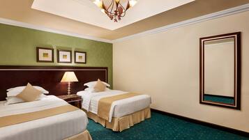 Quarto de hotel com duas camas, um candelabro, quadros nas paredes e um espelho grande.