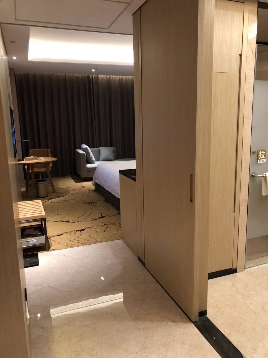 Habitación de hotel con cama, escritorio, silla, armario y puerta de baño.