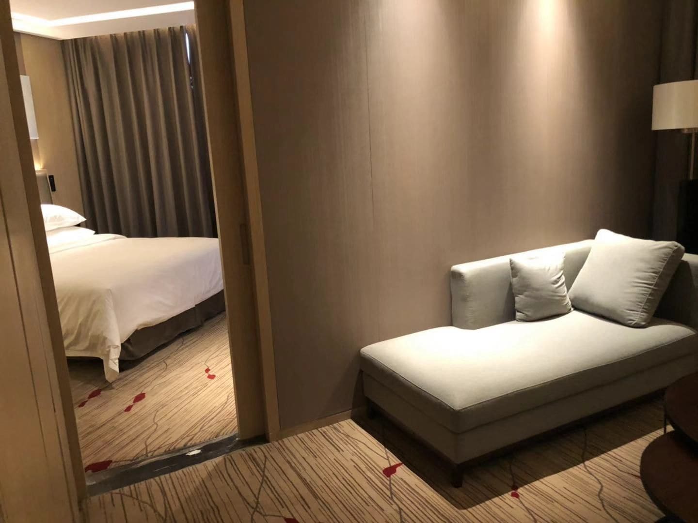 Ein Hotelzimmer mit einem Bett, einer Couch und einem Teppich mit roten Blütenblättern.