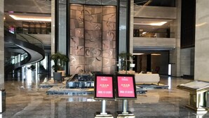 A modern lobby with a curved staircase, a reception desk, and a decorative wall with abstract patterns. - Ramada Wyndham Zhengzhou Xinzheng (Zhengzhou)
