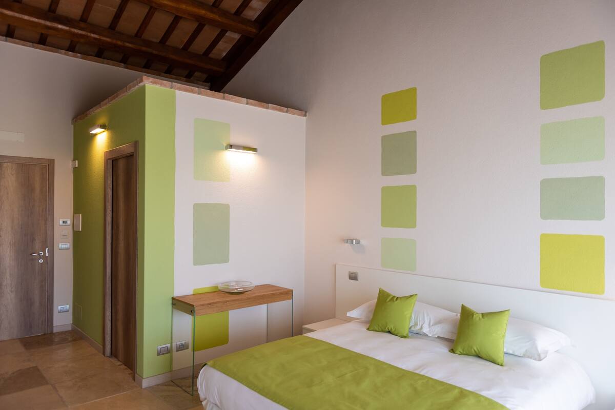 A bedroom with a bed, bedside table, and a wall with square patterns.