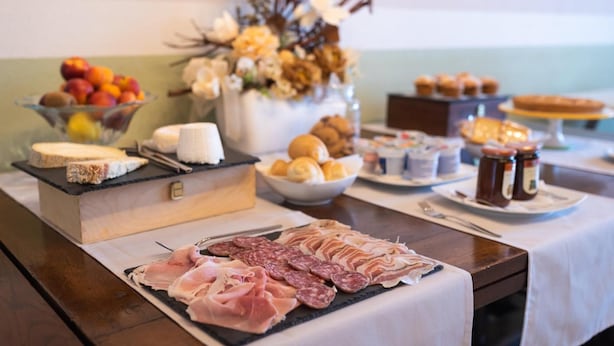 Una mesa de buffet con diferentes alimentos, incluyendo carnes, quesos, frutas y repostería.