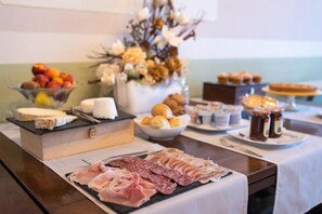 Una mesa de buffet con diferentes alimentos, incluyendo carnes, quesos, frutas y repostería.