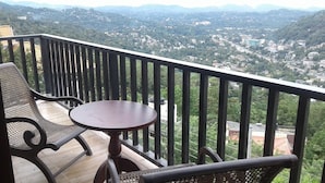 A balcony with a table and chairs overlooking a mountainous landscape. - Lawan One Kandy (Kandy)