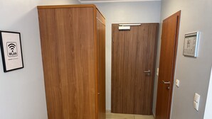 A hallway with wooden doors, a framed WLAN sign, and a small electrical outlet on the wall. - Hotel Mykonos (Eschweiler)