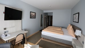 Une chambre d’hôtel équipée d’un lit, d’un bureau, d’une chaise, d’une télévision et d’une douche.