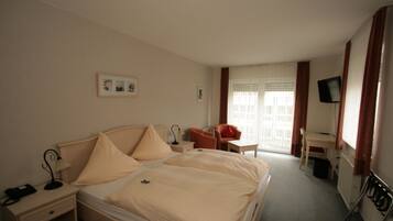 A hotel room with a bed, a desk, a chair, a TV, and a window with curtains.