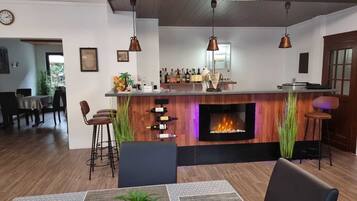 A modern bar area with a fireplace, bar stools, and a dining area with a table and chairs.