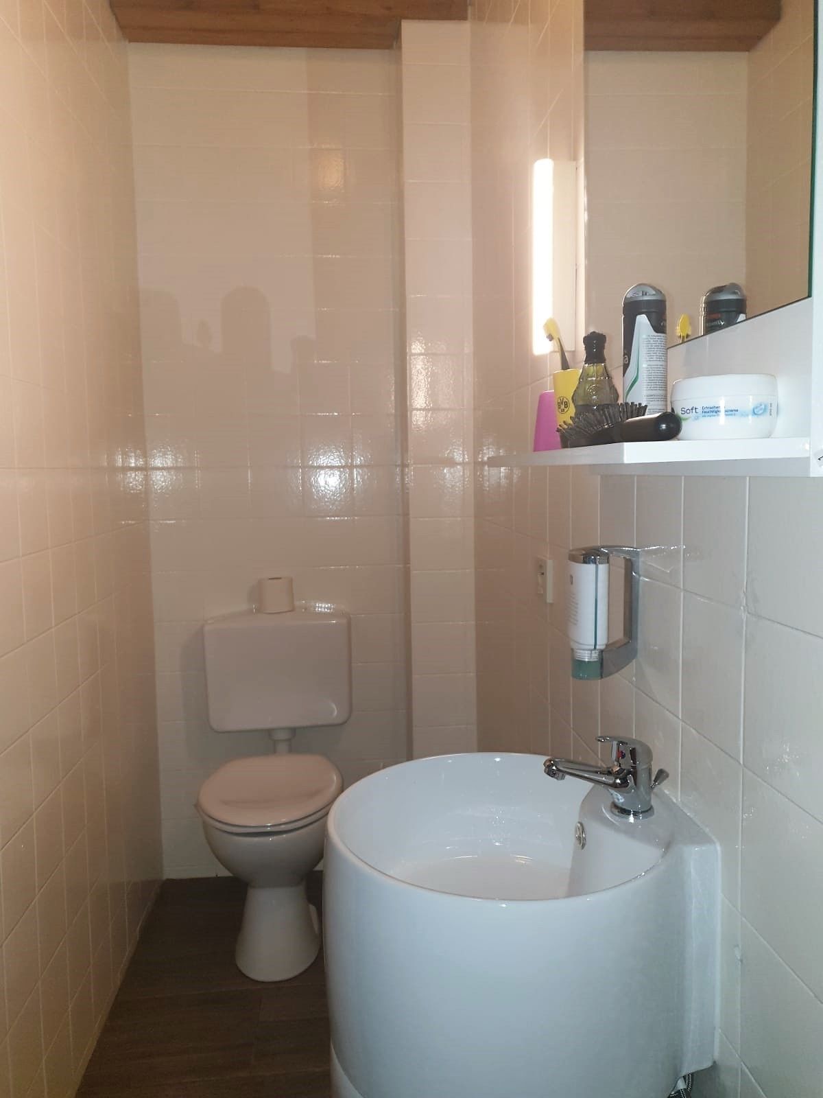 A small bathroom with a toilet, sink, and mirror.