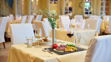 A dining area with tables set for a meal, featuring a centerpiece with flowers and a plate of food.
