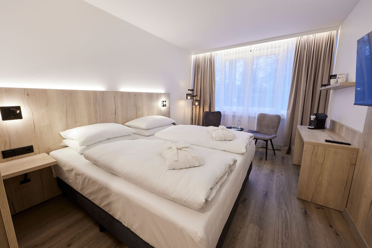 A hotel room with a large bed, bedside tables, a chair, a desk, and a TV.