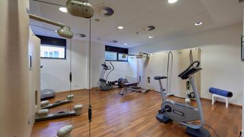 Ein modernes Fitnessstudio mit Trainingsgeräten, Holzboden und einem Fenster, das natürliches Licht hereinlässt.