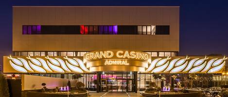 Exterior del edificio Grand Casino Admiral, con un diseño moderno, que presenta un llamativo cartel luminoso y una entrada bien iluminada.