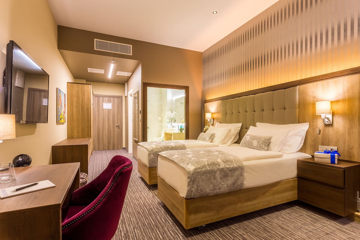 Une chambre d’hôtel avec deux lits, un bureau, une chaise et un miroir.