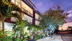 A hotel with a well-lit exterior, multiple balconies, and a variety of potted plants. - Yellow Daisy Villa (Da Nang)