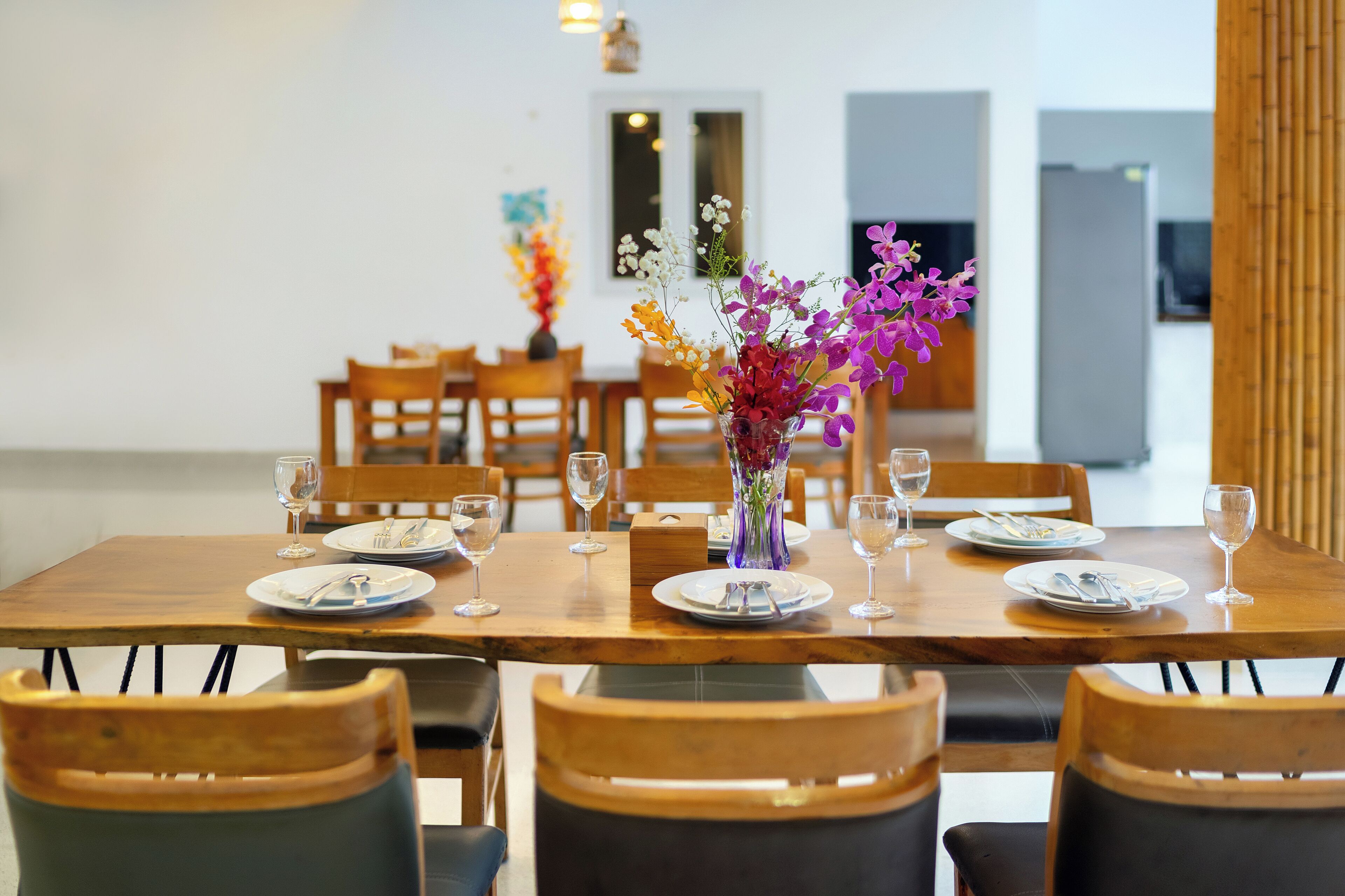 A dining area with a wooden table set for six, surrounded by chairs.