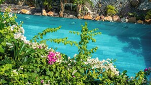 A clear blue pool surrounded by rocks and lush greenery. - Yellow Daisy Villa (Da Nang)
