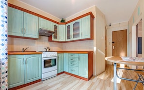 A kitchen with teal cabinets, a white stove, and a wooden countertop.