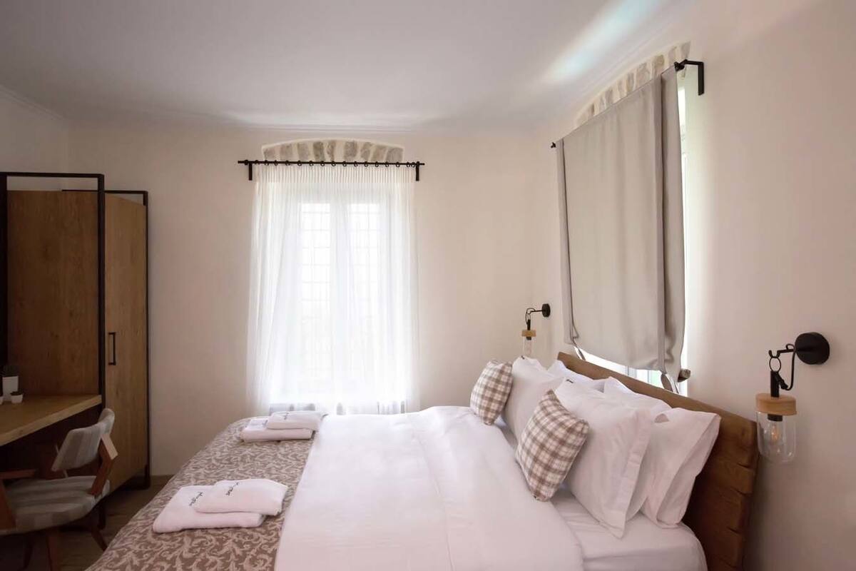 A hotel room with a bed, a desk, a chair, and a wardrobe.