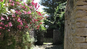 A narrow cobblestone path flanked by stone walls and lush greenery, leading to a gated entrance. - Unique Antistress Oasis Villa Antiqua  (Mali Losinj)