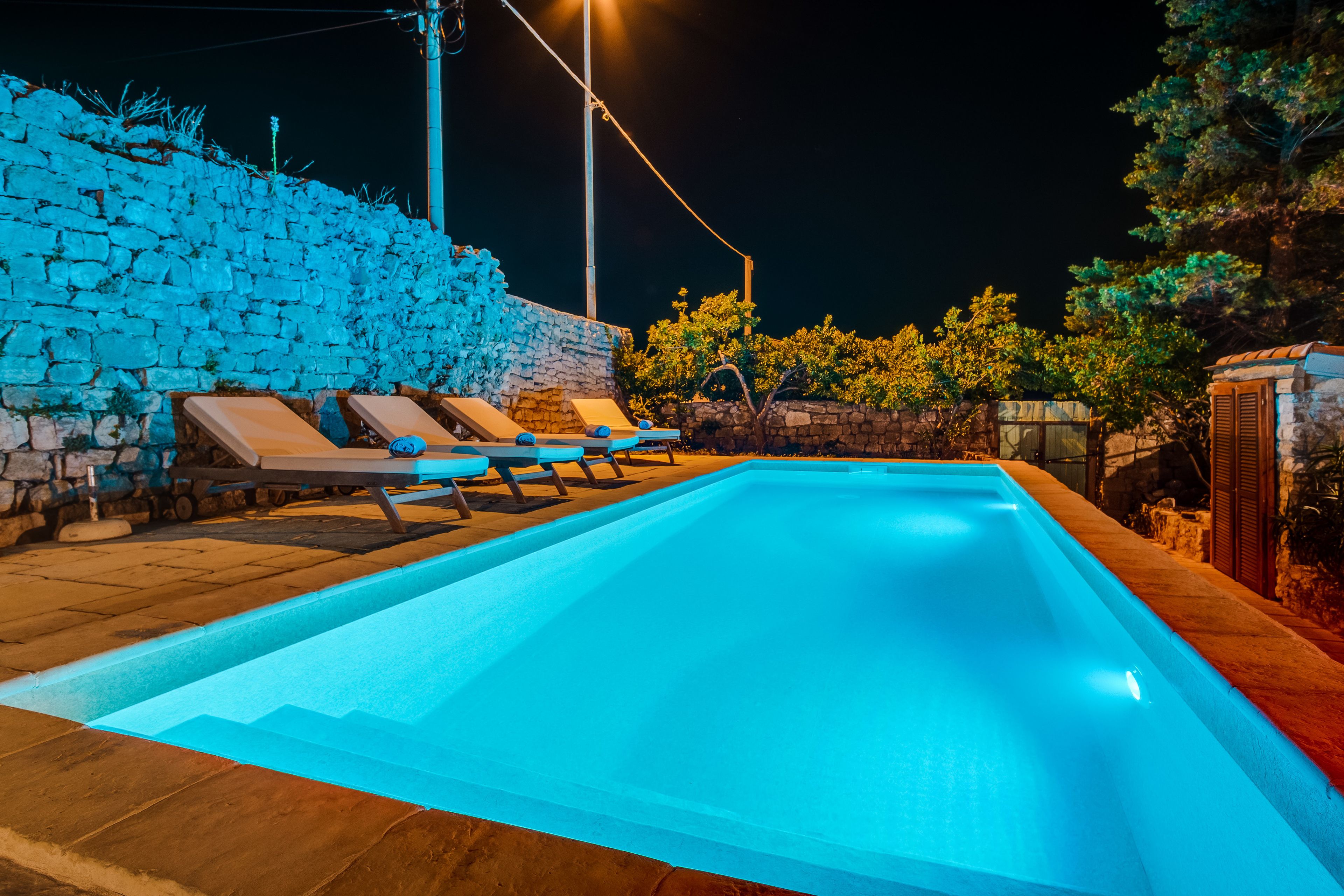 A swimming pool with lounge chairs and stone walls.