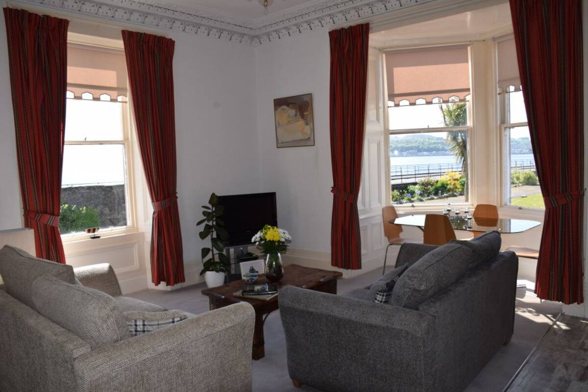 A living room with two sofas, a coffee table, a TV, and a window with curtains.