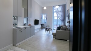 A modern kitchen with a built-in oven, a dining area with a table and chairs, and a living room with a sofa and a TV. - Absyntapart Bulwar Staromiejski (Wroclaw)