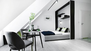 A modern loft bedroom with a skylight, a dining area with a table and chairs, and a built-in sofa with a bike art piece above it. - Absyntapart Bulwar Staromiejski (Wroclaw)